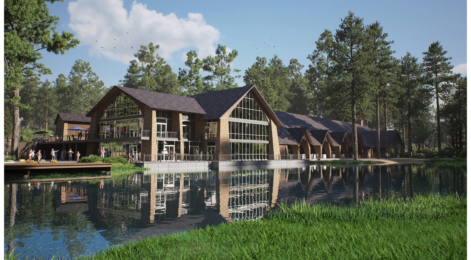 A modern brick building with large windows and peaked rooflines sits beside a calm pond, surrounded by tall pine trees, with several people visible on the deck and grounds.