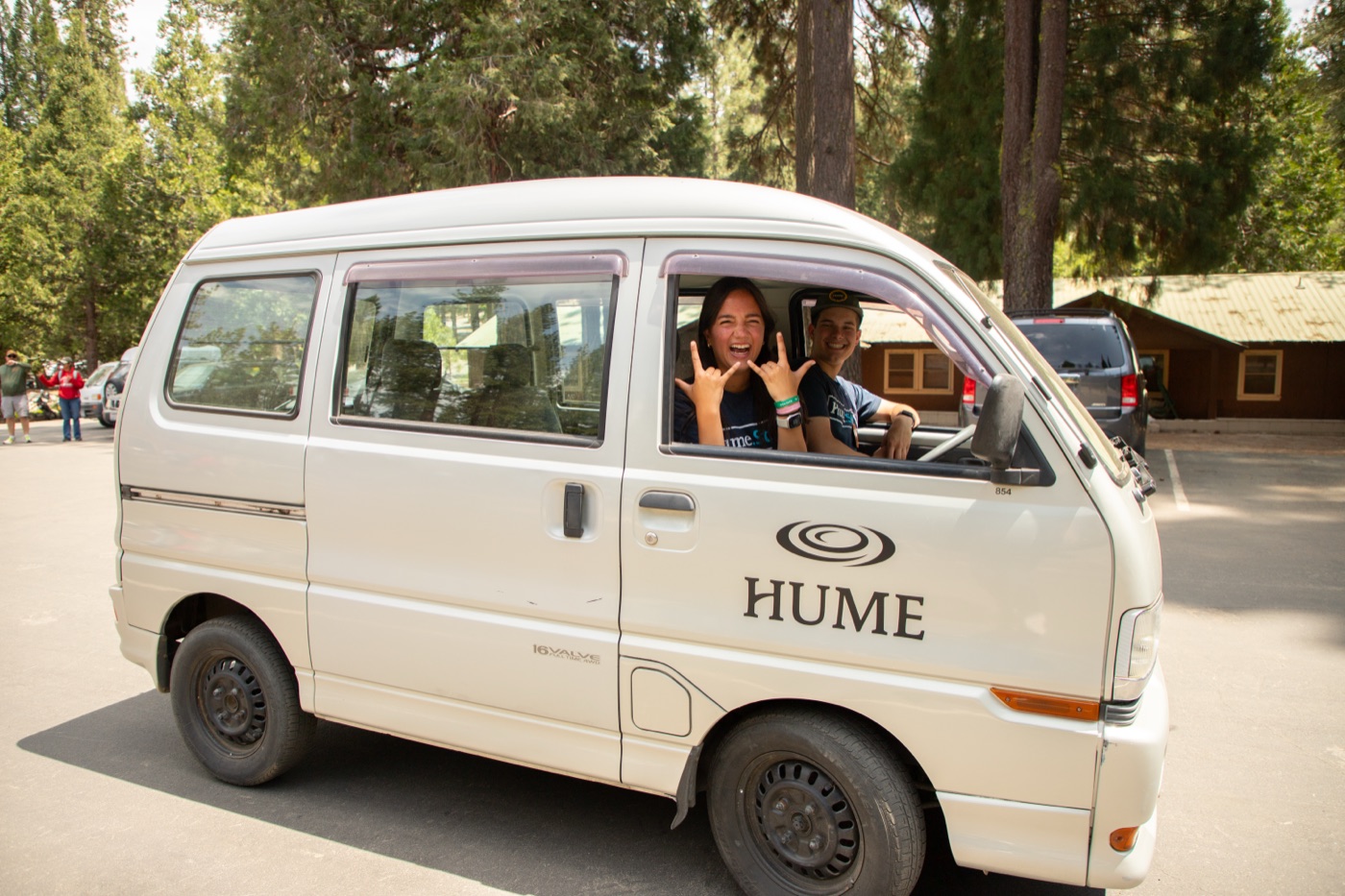 A white Hume mini van with staff waving from the windows.