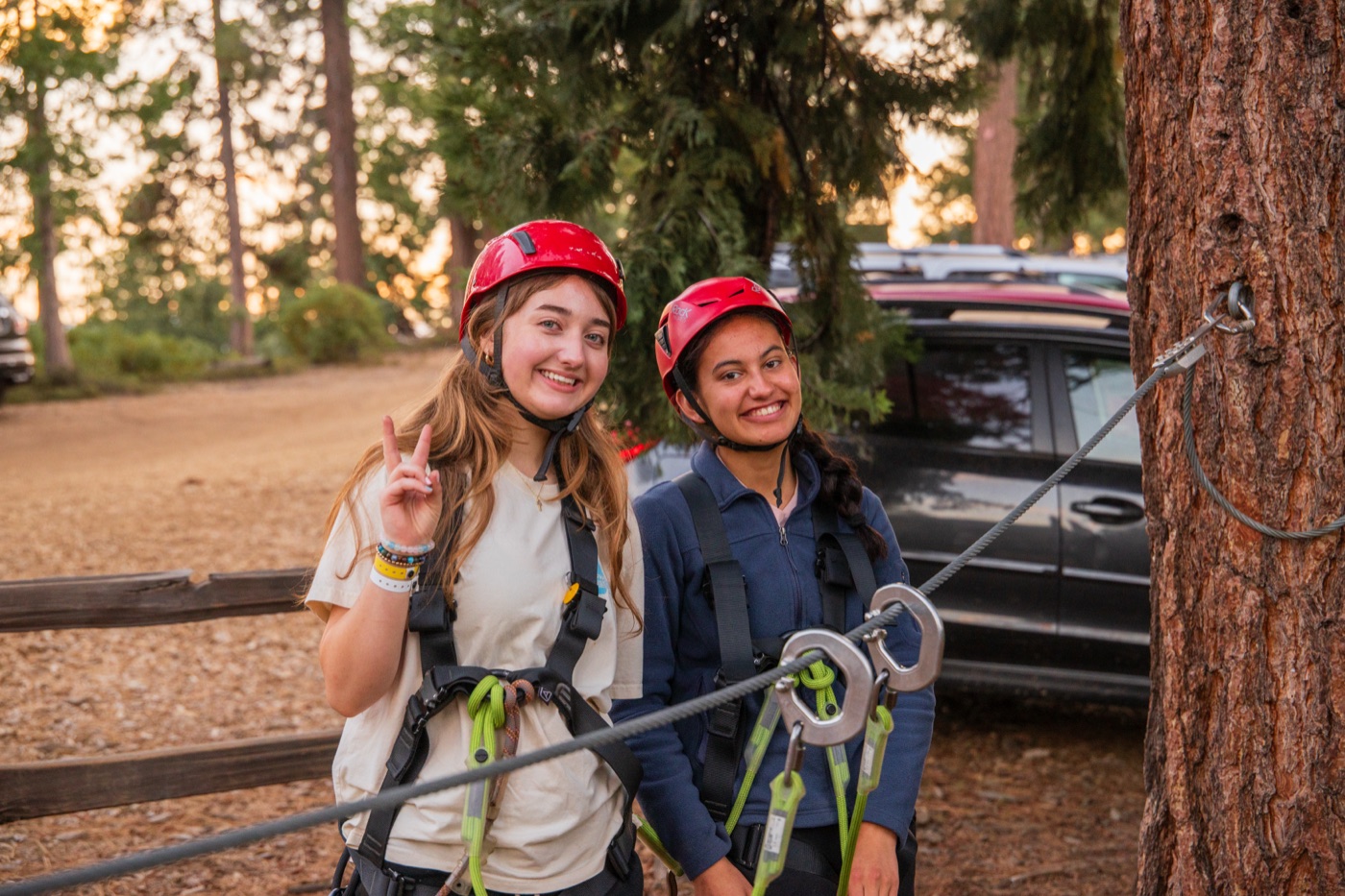 Two campers in helmets and harnesses before a group initiative at Wildwood.