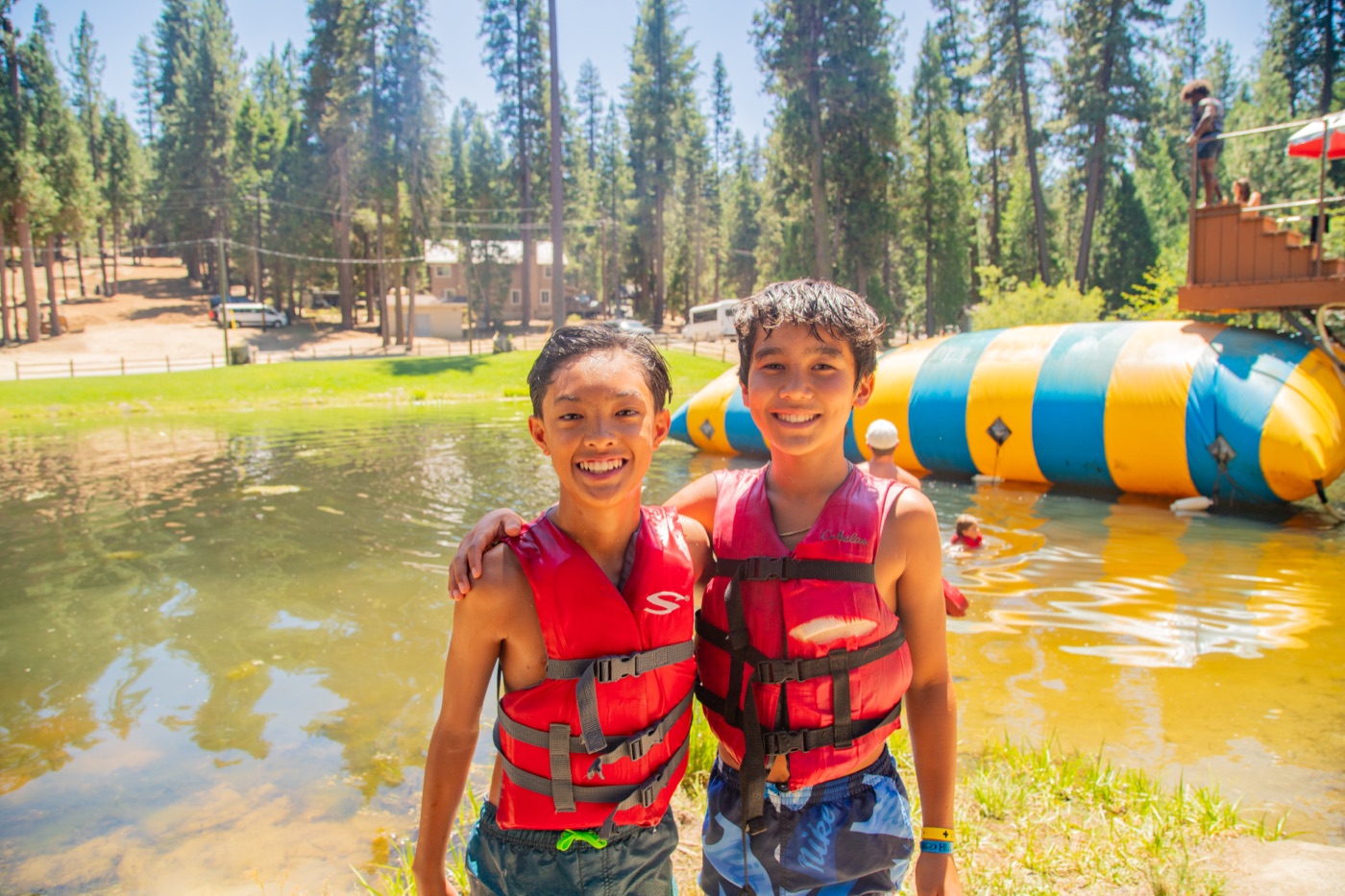 Two campers in life vests in front of the water inflatables at Hume Lake.