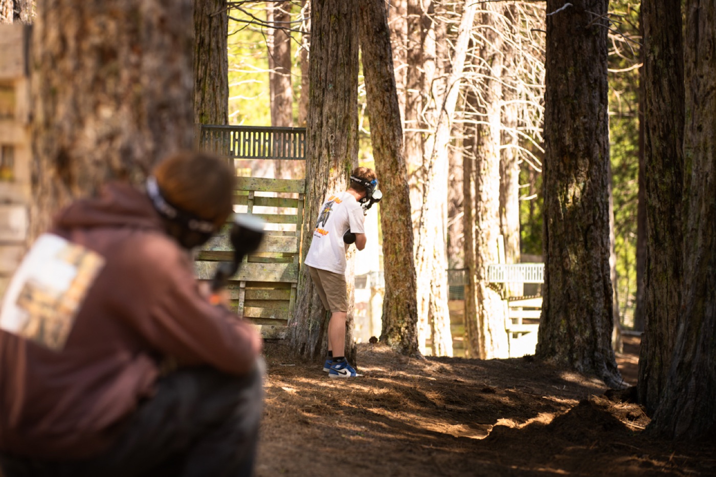 A camper aiming at the paintball range in the woods.
